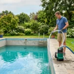 Personne vidant une piscine avec une pompe dans un jardin ensoleillé